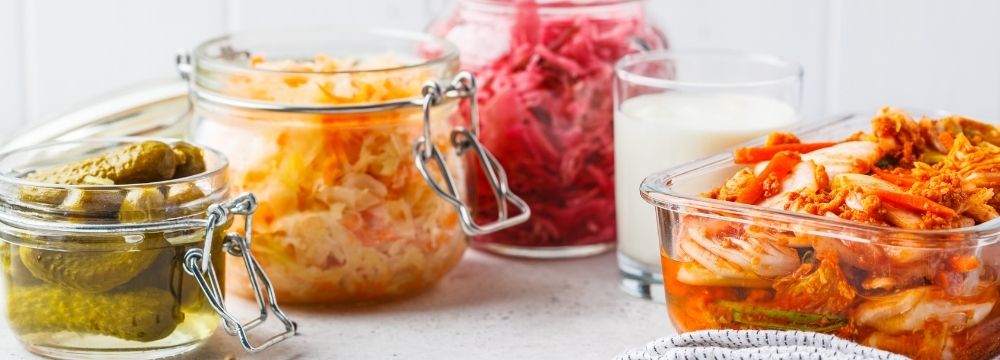 array of probiotic food in jars on counter, pickles, kimchi