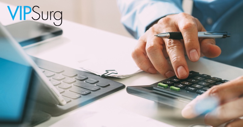 Man with a men in his hand at a desk with a laptop and using a calculator