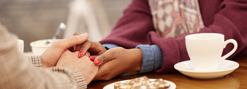 friends holding hands in support while discussing bariatric surgery at a coffee shop