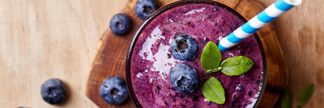 Blueberry smoothie in tall glass on countertop 
