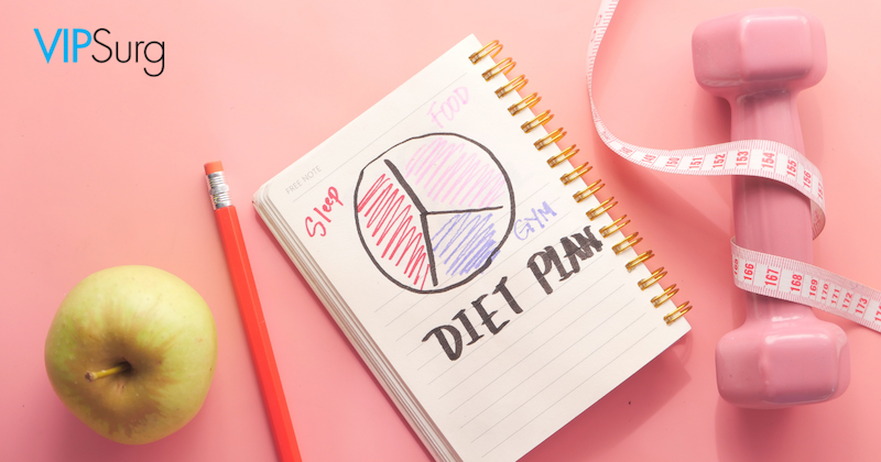 Green apple, red pencil, diet plan notepad, pink dumbbell, and pink measuring tape on light pink background